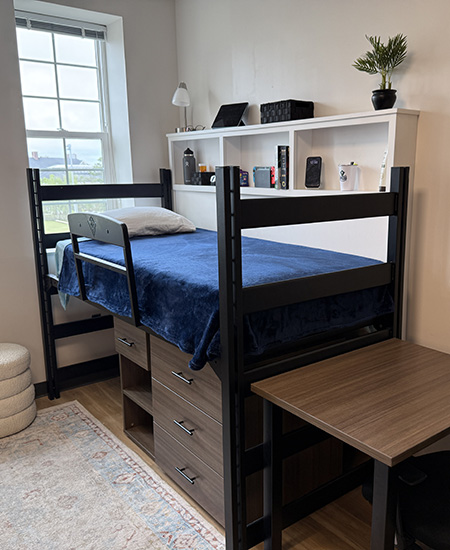 Neatly organized lofted bed setup with Dorm Wise cubby displaying keepsakes and storing bedside essentials.