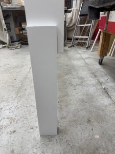 Lower side view of a Dorm Wise cubby showing under-shelf clearance for bins, suitcases, or extra seating beneath.